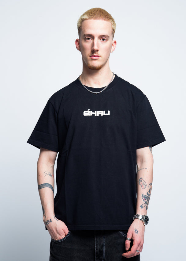 Person wearing a black t-shirt with a logo on a plain background